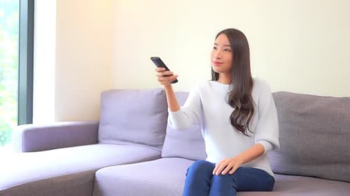 Woman using remote control while sitting on couch