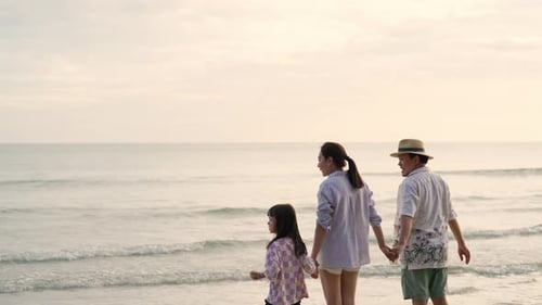 4K Parents with little daughter walking and playing together on the beach at summer sunset.