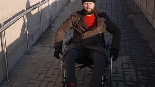 Man in Wheelchair Moves Down Urban Ramp