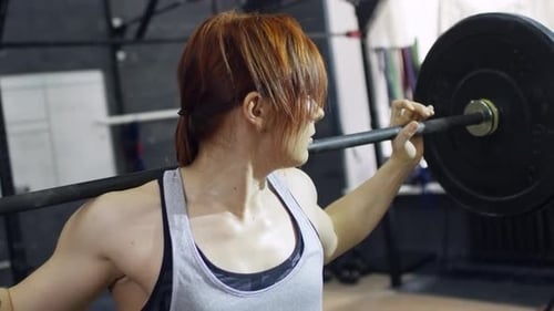 Strong Woman Lifting Barbell During Intense Workout