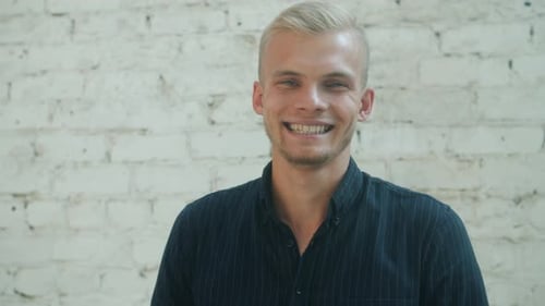 Man Smiling in Front of a White Brick Wall