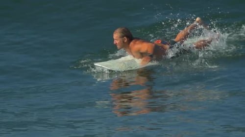 Shirtless Surfer Paddles out in the Ocean