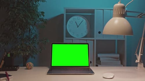 Laptop on the Desk in the Office Shows Green Mockup Screen