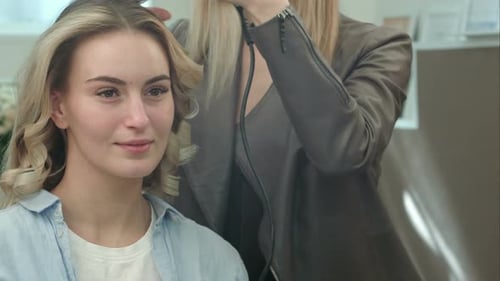 Hairdresser Is Making the Hairstyle, Curls of Hair Strands By Curling Iron for a Smiling Woman