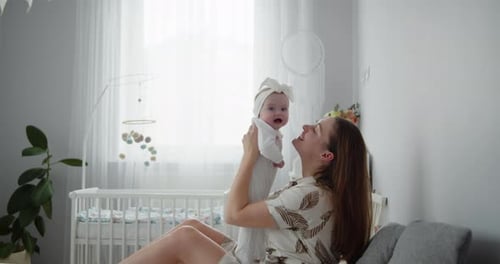 Happy Woman Holding Baby Up in Nursery