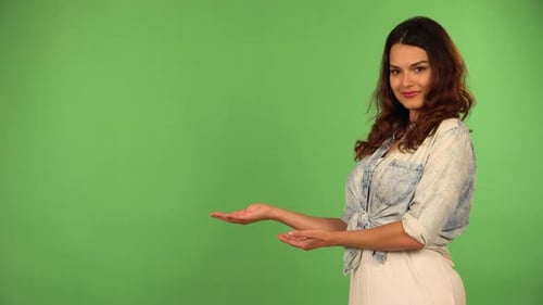 A Young Beautiful Caucasian Woman Presents Something to the Camera with a Smile Green Screen