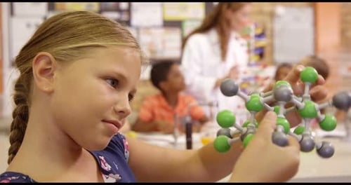 Girl Examines Molecule Model in Science Lab