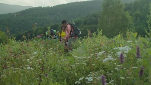 Diverse Multiethnic Tourist with Backpacks Ascending Steep Mountain Hill During Trek
