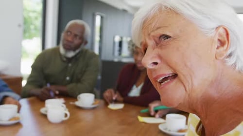 Senior Adults Play Bingo Together at Table Indoors
