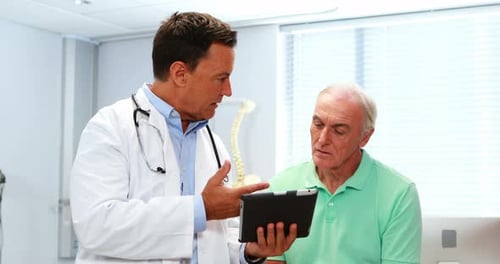 Doctor and Patient Discussing on Tablet in Clinic