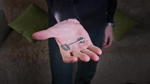 Male Hand Holding a Home Key and Showing It to the Camera CloseUp