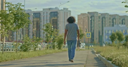 Brutal Man with Long Hair Walks Along the Sidewalk of the City
