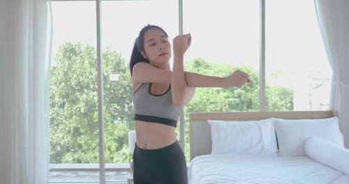 Young Woman Stretches Arms in Bedroom