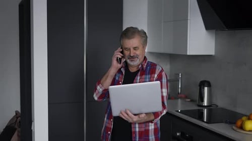 Adult with Laptop Talking on Mobile Phone Indoors