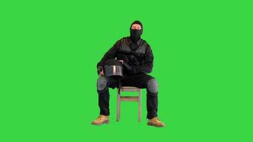 Policier anti-émeute assis avec son casque éteint se reposant sur un écran vert Chroma Key