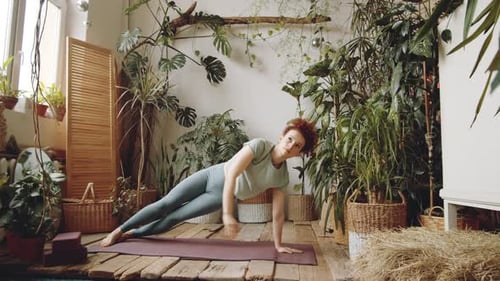 Young Fit Woman Practicing Side Plank during Home Yoga Workout