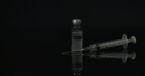 Syringe and Vaccine Vial on Reflective Surface