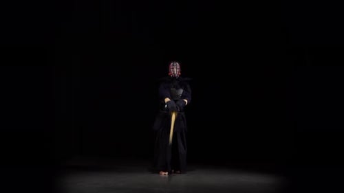 Starker Kendo Guru übt Kampfkunst mit dem Bambus-Bokken auf schwarzem Hintergrund.
