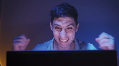 Man Rejoices at Victory in Online Game Looking at Laptop