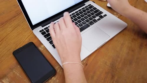 Girl hands typing on the keyboard of a silver laptop.