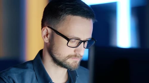 Nahaufnahme eines konzentrierten Mannes mit Brille, der am Computer arbeitet