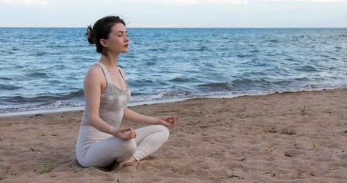 Woman practicing yoga outside in lotus pose on beach