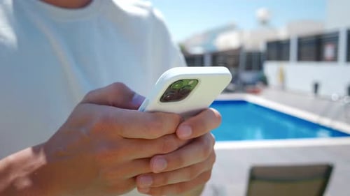 Man Using Phone by Pool on Sunny Day