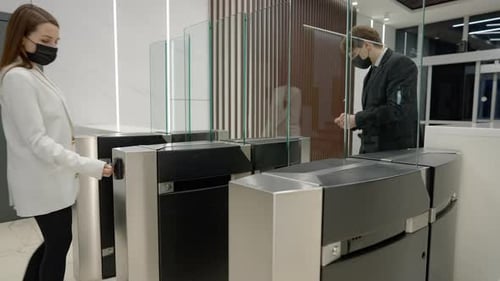 Un hombre y una mujer caucásicos utilizan un pase de entrada sin contacto en la oficina por la pandemia de coronavirus