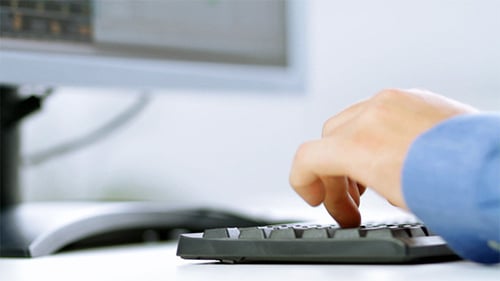 Hands Typing on Black Keyboard in Office