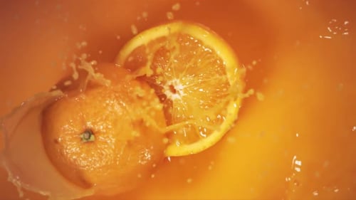 Sliced Orange Splashing into Fresh Orange Juice