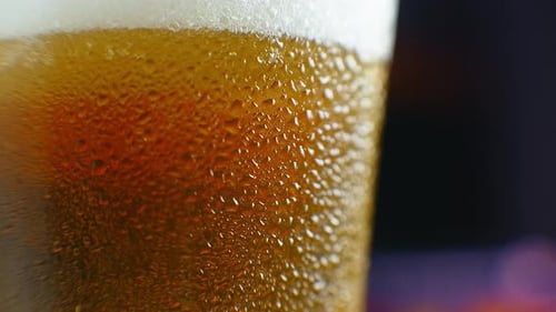 Nahaufnahme Zeitlupe: Kaltes Bier im Glas Große Tropfen und Blasen im Bier.