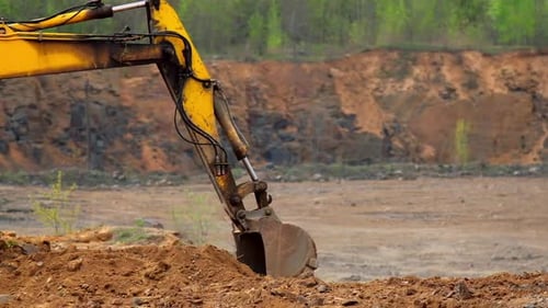 Yellow Excavator Digging in Dirt Pile