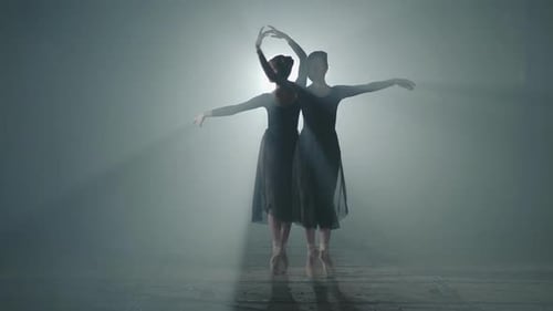 Two Ballerinas Dancing Gracefully in Foggy Studio