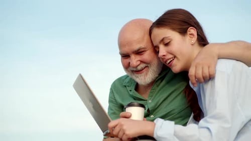 Senior Man and Young Woman with Laptop Outdoors