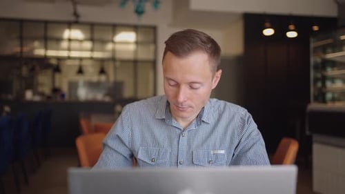 Young Adult Working on Laptop in Cafe