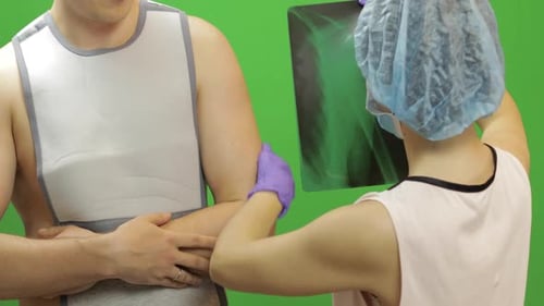 Man with Shoulder Injury. Nurse Examines X-ray. Bandage for Fixing Shoulder