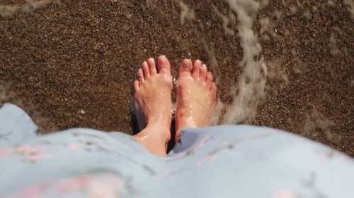 Woman's Feet Enjoying Gentle Waves on Beach