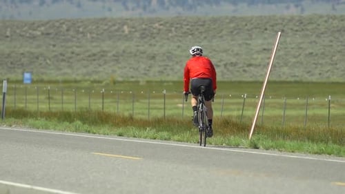 A man road biking on a scenic road.