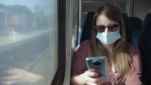 Woman in mask using a phone on the train
