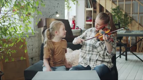 Woman Plays Violin for Child on Couch