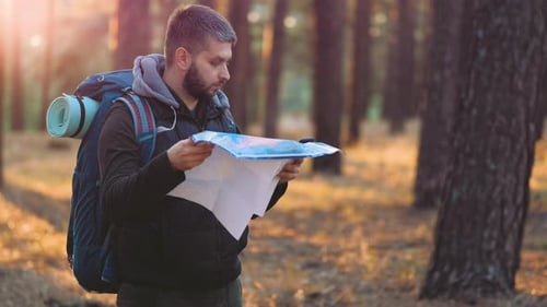 Man with Backpack Navigates Forest With Map