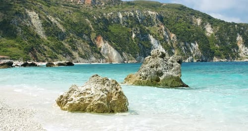 Clear Sea Waves Splashing on Peaceful White Beach with Pebbles Seascape with Rocks in Background