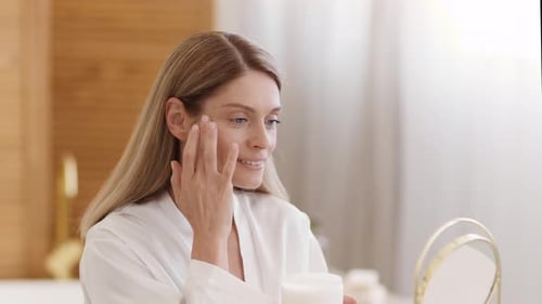 Woman Applying Moisturizing Cream in Bathroom