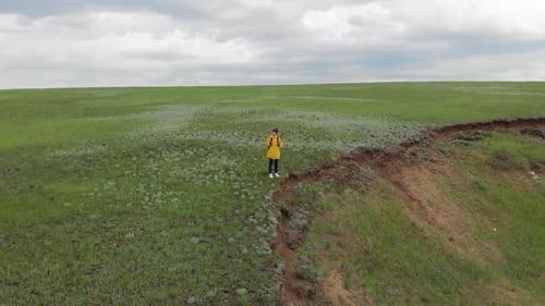 Person Standing on Grassy Bluff Overlooking Landscape