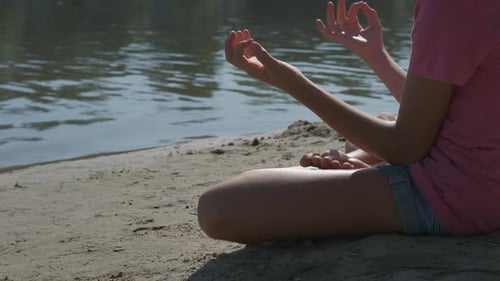 Child Meditating Peacefully on Sunny Beach by Water