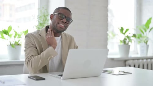 African Man Having Neck Pain While Using Laptop in Office