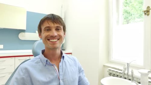 Joven con dientes blancos y sanos sonriendo y mirando a la cámara en el dentista