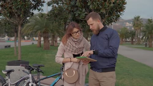Junger Mann und Frau betrachten die Stadtkarte auf dem Tablet-Bildschirm und stehen im Park