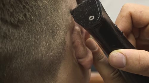 Mann und Friseur mit Trimmer schneiden Haare im Shop