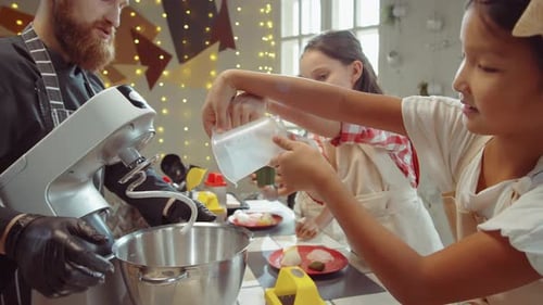Kids Adding Ingredients to Mixer Bowl on Culinary Masterclass